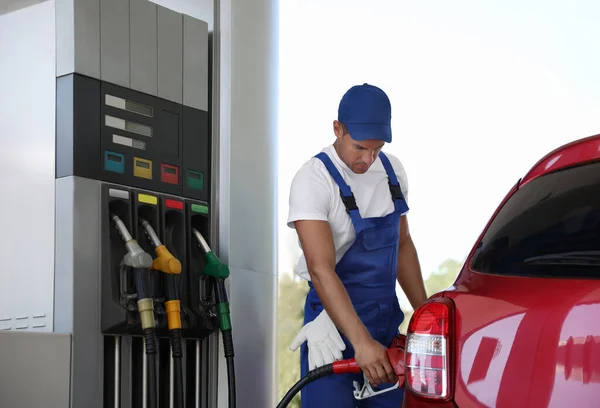 Worker refueling car at modern gas station