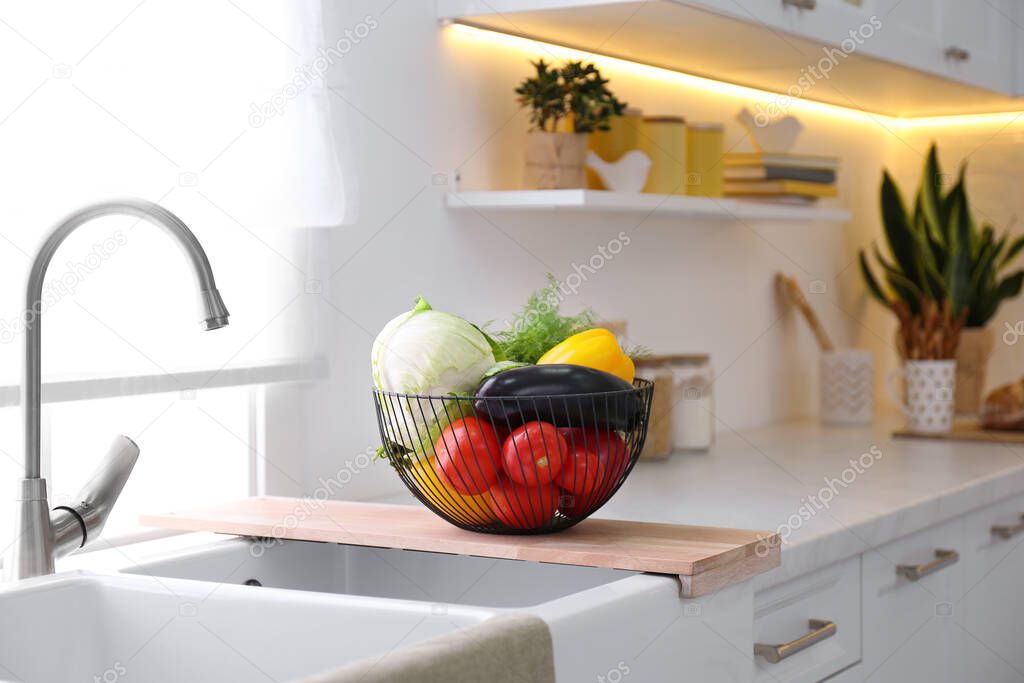 Basket full of different vegetables on wooden board in modern kitchen