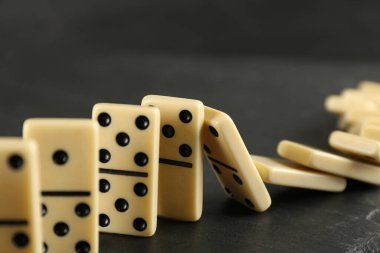 Beyaz domino taşları koyu gri masaya düşüyor.