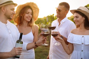 Arkadaşlar, güneşli bir günde üzüm bağında kadeh tokuşturuyorlar.