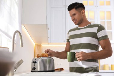 Adam mutfak tezgahında modern tost makinesi kullanıyor.