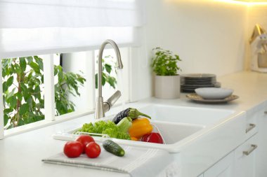 Birçok taze sebze musluk suyunun altında mutfak lavabosunda.