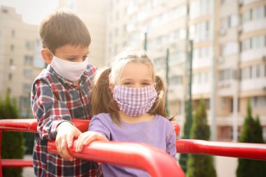 Covid-19 karantinası sırasında çocuk parkında tıbbi maskeli küçük çocuklar