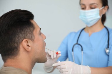 Doktor klinikteki adamdan DNA testi için örnek alıyor.
