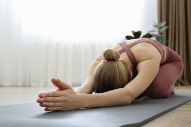 Yoga stüdyosunda uzun çocuk Asana pratiği yapan genç bir kadın. Utthita Balasana pozu