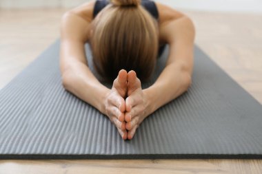 Yoga stüdyosunda uzun çocuk Asana alıştırması yapan genç bir kadın. Ellerine odaklan. Utthita Balasana pozu
