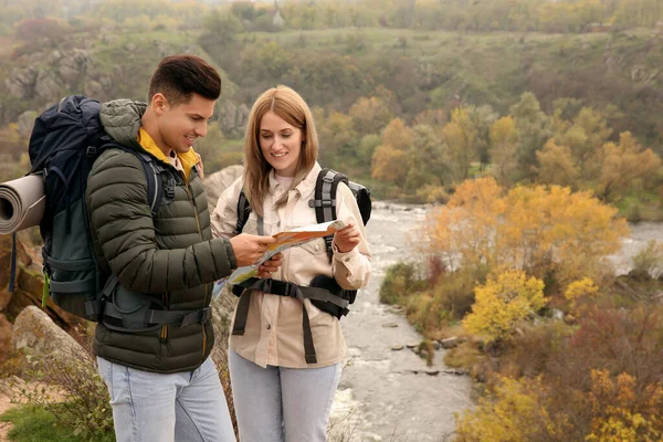 Couple of travelers with backpacks and map planning trip in mountains. Autumn vacation