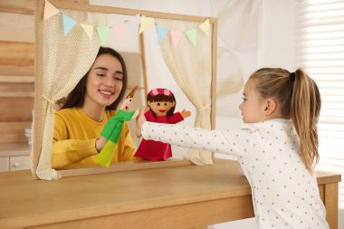 Mother performing puppet show for her daughter at home clipart