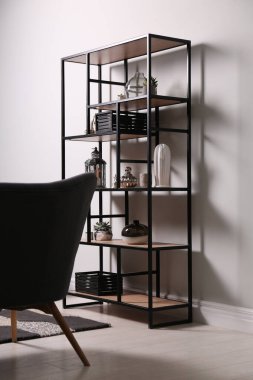 Odadaki beyaz duvarın yanında farklı dekorları ve çiçekleri olan raflar. İç tasarım