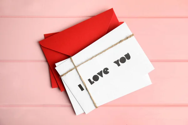 有文字的卡片我爱你 红包在粉红的木桌上 平铺在地板上 — 图库照片