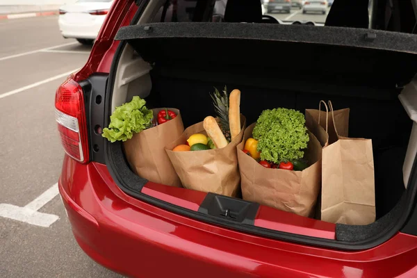 Bags full of groceries in car trunk outdoors