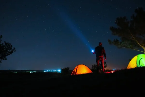 キャンプ場のテントの近くに明るい懐中電灯を持つ男は夜に屋外 — ストック写真
