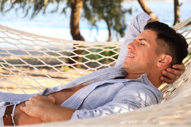 Sahilde hamakta dinlenen bir adam. Yaz tatili