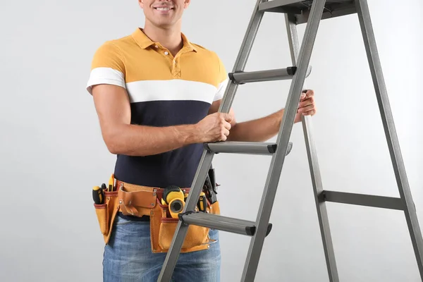 Professioneller Bauarbeiter Mit Metallleiter Auf Grauem Hintergrund Nahaufnahme — Stockfoto