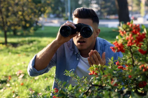 Jealous man with binoculars spying on ex girlfriend in park