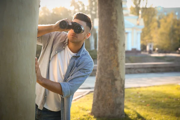 Jealous man with binoculars spying on ex girlfriend in park