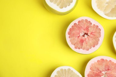 Sarı arka planda taze kesilmiş pomelo meyveleri, düz uzanmış. Metin için boşluk