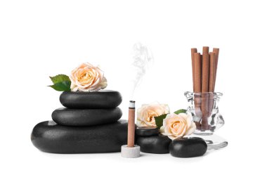Yanan tütsü çubuğu, güller ve beyaz arka planda spa taşlarıyla kompozisyon