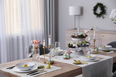 Güzel Paskalya sofrası, yanan mumlar ve kapalı mekanda çiçek dekoru.