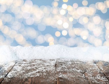 Tahta yüzey karla kaplı ve arka planda bulanık Noel ışıkları, bokeh etkisi 