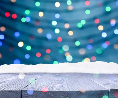 Tahta yüzey karla kaplı ve arka planda bulanık Noel ışıkları, bokeh etkisi 