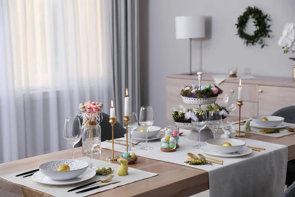 Güzel Paskalya sofrası, yanan mumlar ve kapalı mekanda çiçek dekoru.