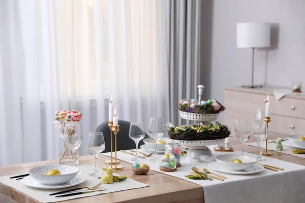 Güzel Paskalya sofrası, yanan mumlar ve kapalı mekanda çiçek dekoru.