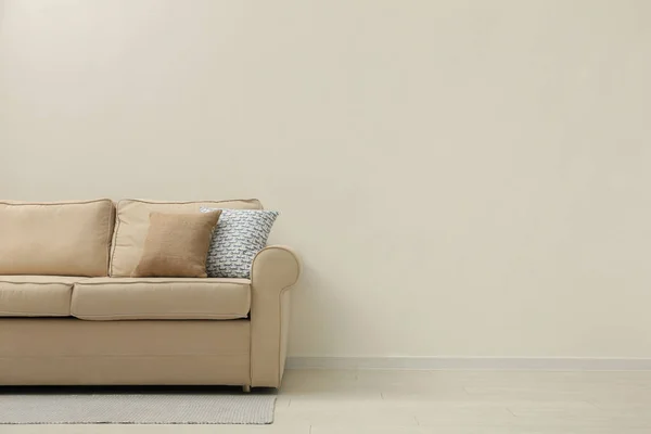 Comfortable sofa near beige wall in living room interior. Space for text