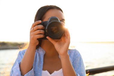 Genç fotoğrafçı dışarıda profesyonel kamerayla fotoğraf çekiyor.
