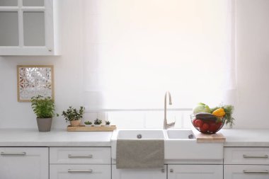 Modern mutfakta tahtanın üzerinde farklı sebzelerle dolu bir sepet.