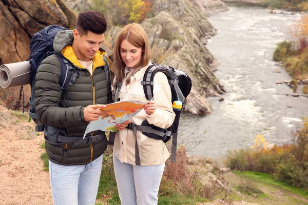 Couple of travelers with backpacks and map planning trip in mountains. Autumn vacation