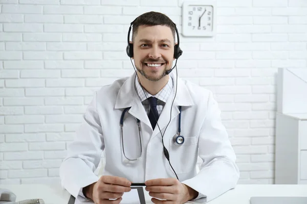 Orvos Fülhallgatóval Asztalnál Klinikán Egészségügyi Forródrót — Stock Fotó