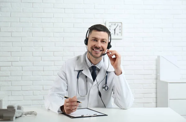 Γιατρός Ακουστικά Που Κάθεται Στο Γραφείο Στην Κλινική Γραμμή Εξυπηρέτησης — Φωτογραφία Αρχείου