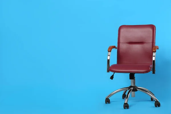 Comfortable office chair on light blue background, space for text