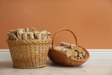 Kahverengi duvarın yanında yakacak odunları olan sepetler.