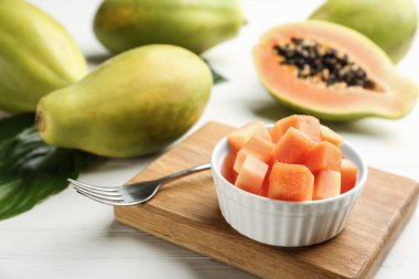 Beyaz ahşap masada kasede taze kesilmiş papaya.