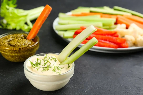 Celery sticks with dip sauce in glass bowl on black table