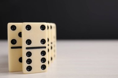 Tahta masadaki Domino fayansları siyah arka plana karşı, yakın plan. Metin için boşluk