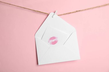 Beyaz zarf ve kart. Pembe arka planda sicimde dudak izi var. Aşk mektubu