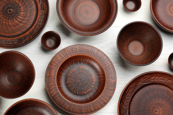 Set of clay utensils on white wooden table, flat lay