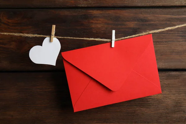 木製の背景に対して双子にぶら下がっている赤い封筒と紙の心 ラブレター — ストック写真
