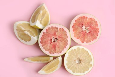 Pembe arka planda taze kesilmiş pomelo meyveleri.
