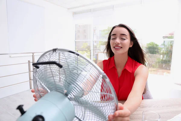 職場でファンからの空気の流れを楽しむ若い女性 夏の暑さ — ストック写真