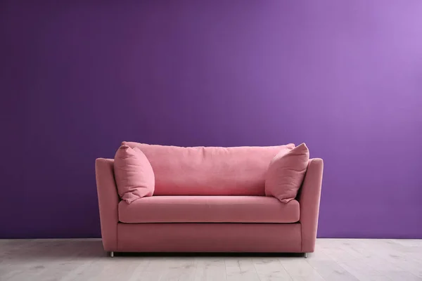 舒适的粉红色沙发靠近客厅内部的紫色墙壁 案文的篇幅 — 图库照片