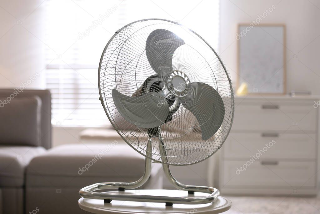 Modern electric fan on white table in living room