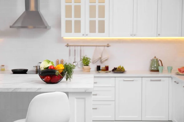 現代的なキッチンの白いテーブルの上にさまざまな野菜でいっぱいのバスケット — ストック写真