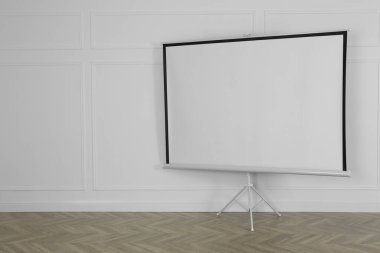 Beyaz duvarın yanındaki boş projeksiyon ekranı. Tasarım için boşluk