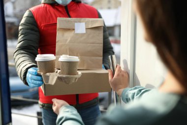 Kurye, kapıdaki kadına siparişini veriyor, kapatıyor. Covid-19 karantinası sırasında teslimat servisi