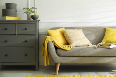 Kanepeli şık bir oturma odası. İç tasarım gri ve sarı renklerde.