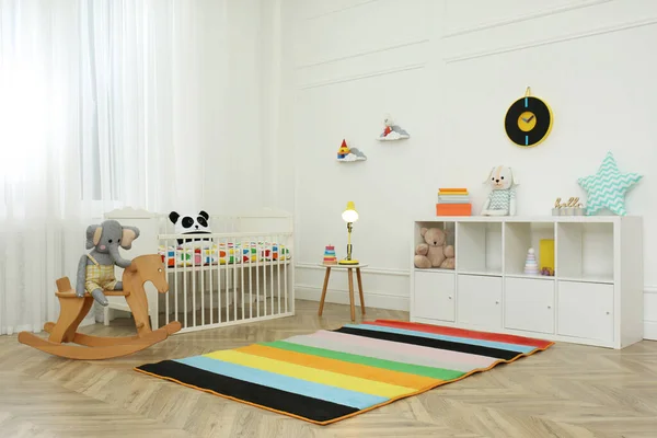 Cute baby room interior with stylish furniture and toys